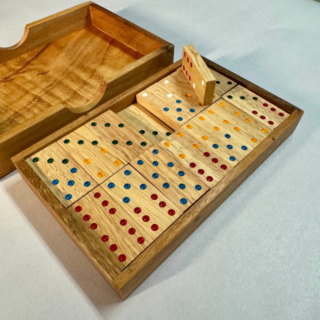 Double 6 wooden domino set with one tile standing upright to show its thickness and colored pips.