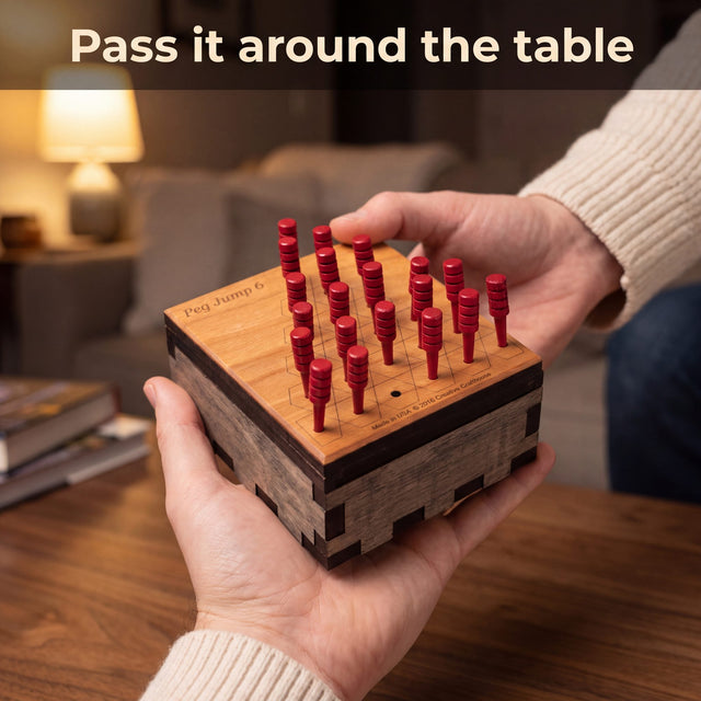 Adult holding the loaded Peg Jump 6 out across a coffee table to pass the next turn. Headline: Pass it around the table.