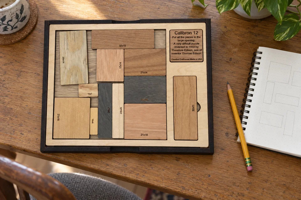 Generated home desk scene of Creative Crafthouse Calibron 12 in its storage layout beside a notebook and pencil; the shown layout is not the square solution