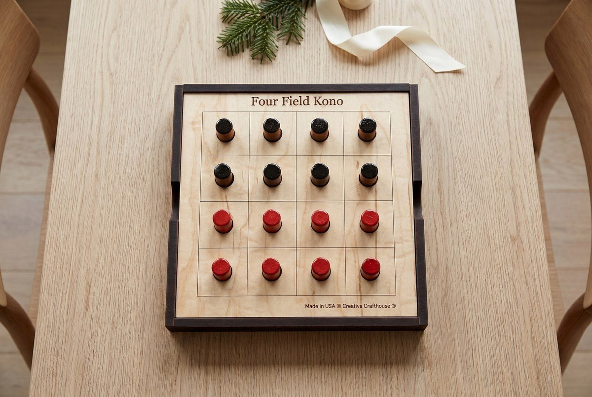 Creative Crafthouse Four Field Kono wooden board on a table, with eight black and eight red pegs in the starting grid