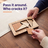 Two people passing the Cruiser puzzle across a table, one holding a loose piece, with the headline Pass it around. Who cracks it?