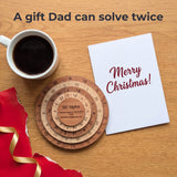 Overhead view of the 60 Alpha puzzle on an oak table beside a Merry Christmas card, a cup of black coffee, torn red wrapping and gold ribbon. Headline: A gift Dad can solve twice.