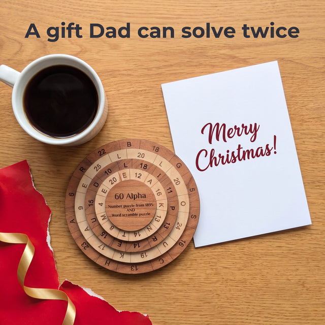 Overhead view of the 60 Alpha puzzle on an oak table beside a Merry Christmas card, a cup of black coffee, torn red wrapping and gold ribbon. Headline: A gift Dad can solve twice.