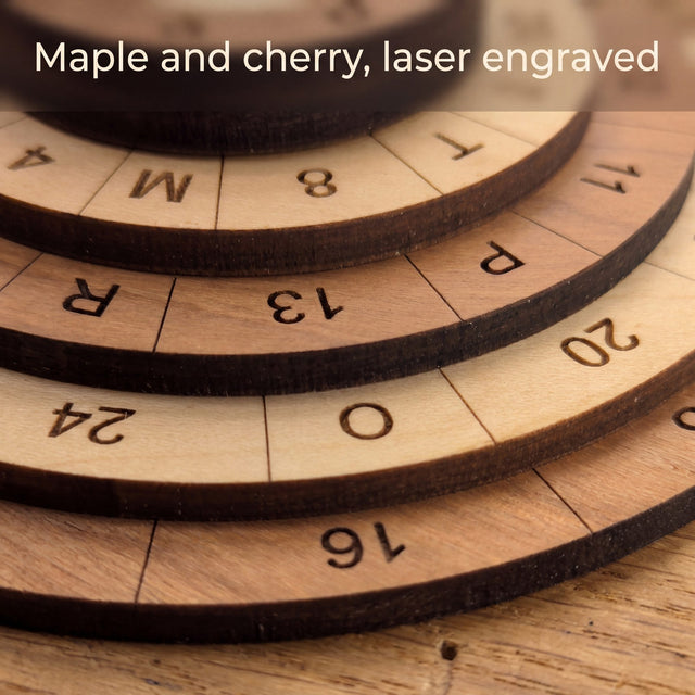 Close up of the laser engraved numbers and letters on the stepped maple and cherry rings of the 60 Alpha puzzle. Headline: Maple and cherry, laser engraved.