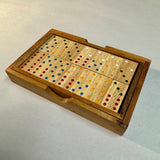 Double 6 wooden dominoes with colored pips arranged in their fitted wooden box.