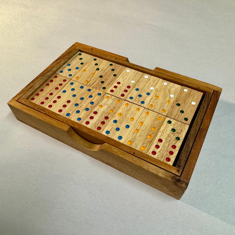 Double 6 wooden dominoes with colored pips arranged in their fitted wooden box.