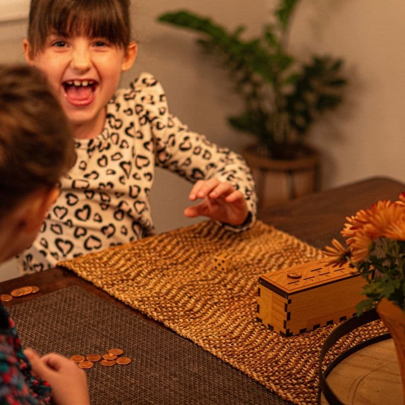 Emma showing extreme joy after winning a game of penny drop with her family at the kitchen table.