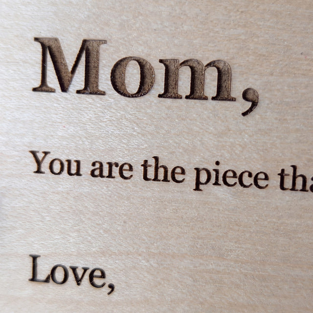Close up of laser engraved serif lettering burned into pale Baltic birch wood grain on a Wood Message Card