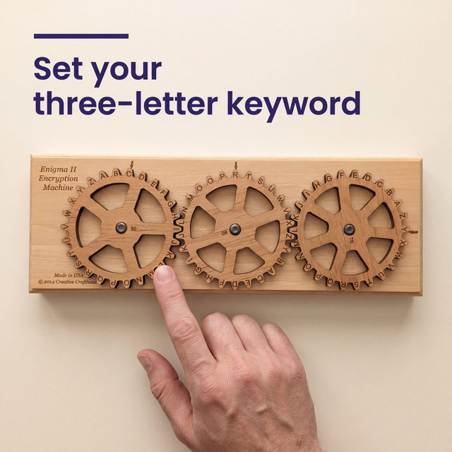 A fingertip setting a lettered gear on the Enigma II Small cipher machine, with the headline Set your three-letter keyword.