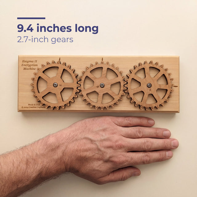 The Enigma II Small beside a flat hand for scale, labelled 9.4 inches long with 2.7 inch gears.