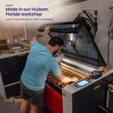 A Creative Crafthouse craftsman loading wood into the laser cutter, with the headline Made in our Hudson, Florida workshop.