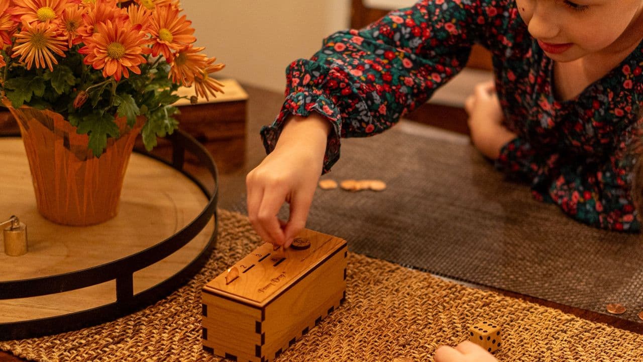 A girl playing the game penny drop at the kitchen table. this is a thumbnail for a video where she explains the rules of the penny drop game.