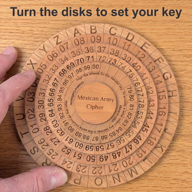 Adult fingertips turning a disk of the Mexican Army Cipher Wheel on an oak desk, seen from above