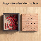 Open Peg Jump 6 box with the red pegs and spare stored inside, its engraved cherry lid beside it. Headline: Pegs store inside the box.