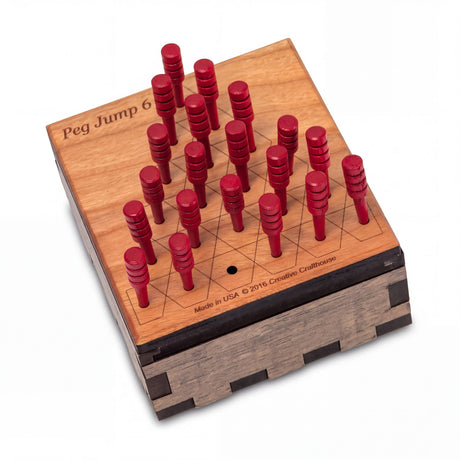 Creative Crafthouse Peg Jump 6 on white: engraved cherry lid board with 20 red pegs and one empty hole, on its finger-jointed storage box.