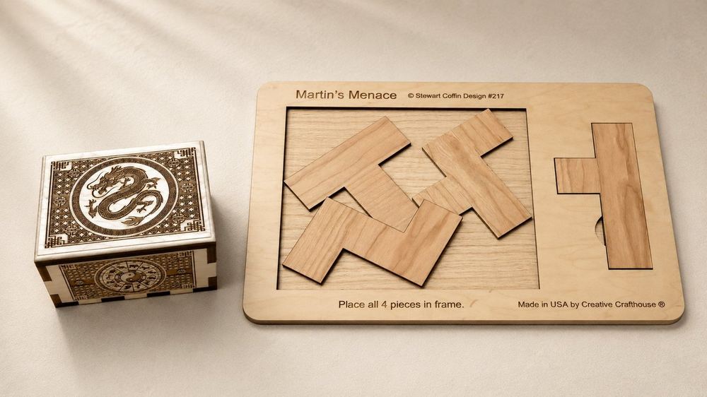 A dragon-engraved wooden puzzle box beside a large Martin's Menace four-piece puzzle