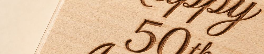 Close-up of a personalized wood engraving reading Happy 50th