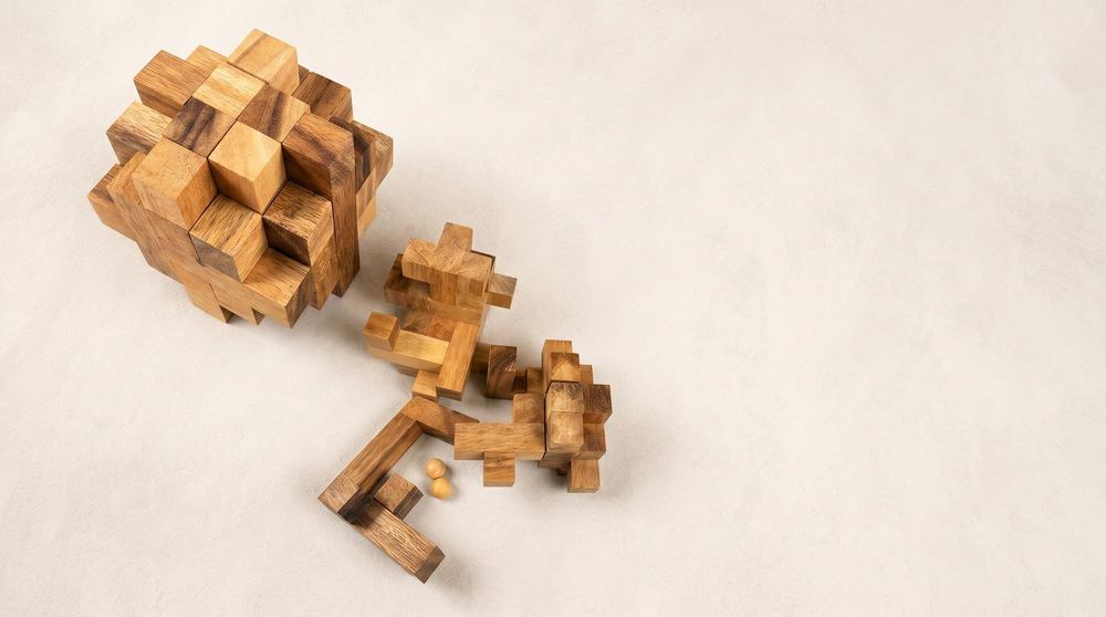 Wooden burr puzzles shown assembled and as loose interlocking pieces