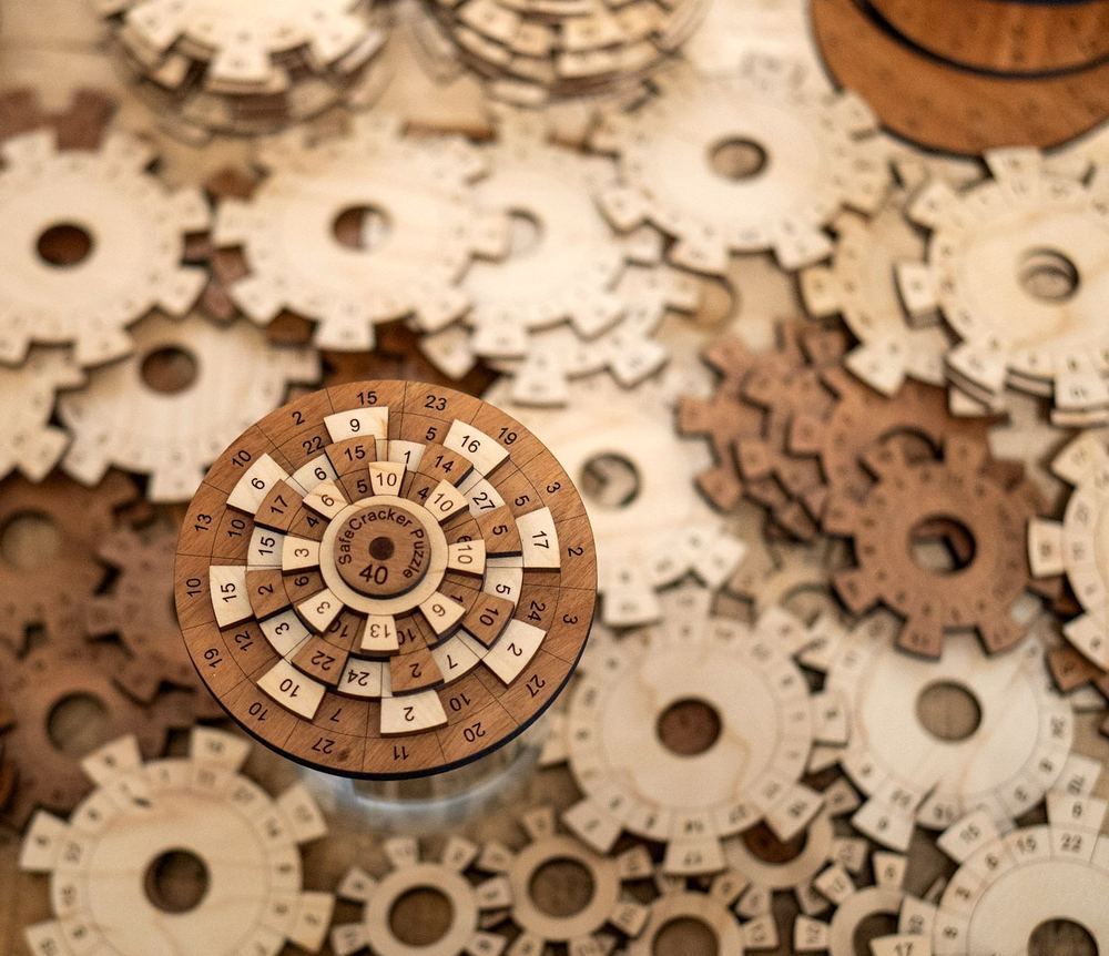 A Safecracker 40 wooden number puzzle standing among scattered circular wooden puzzle parts
